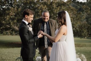 Josh Withers smiling as a couple exchange rings during their wedding ceremony